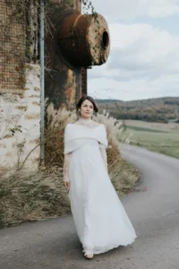 Mariée en robe et maille sous la neige pour un mariage d’hiver chic