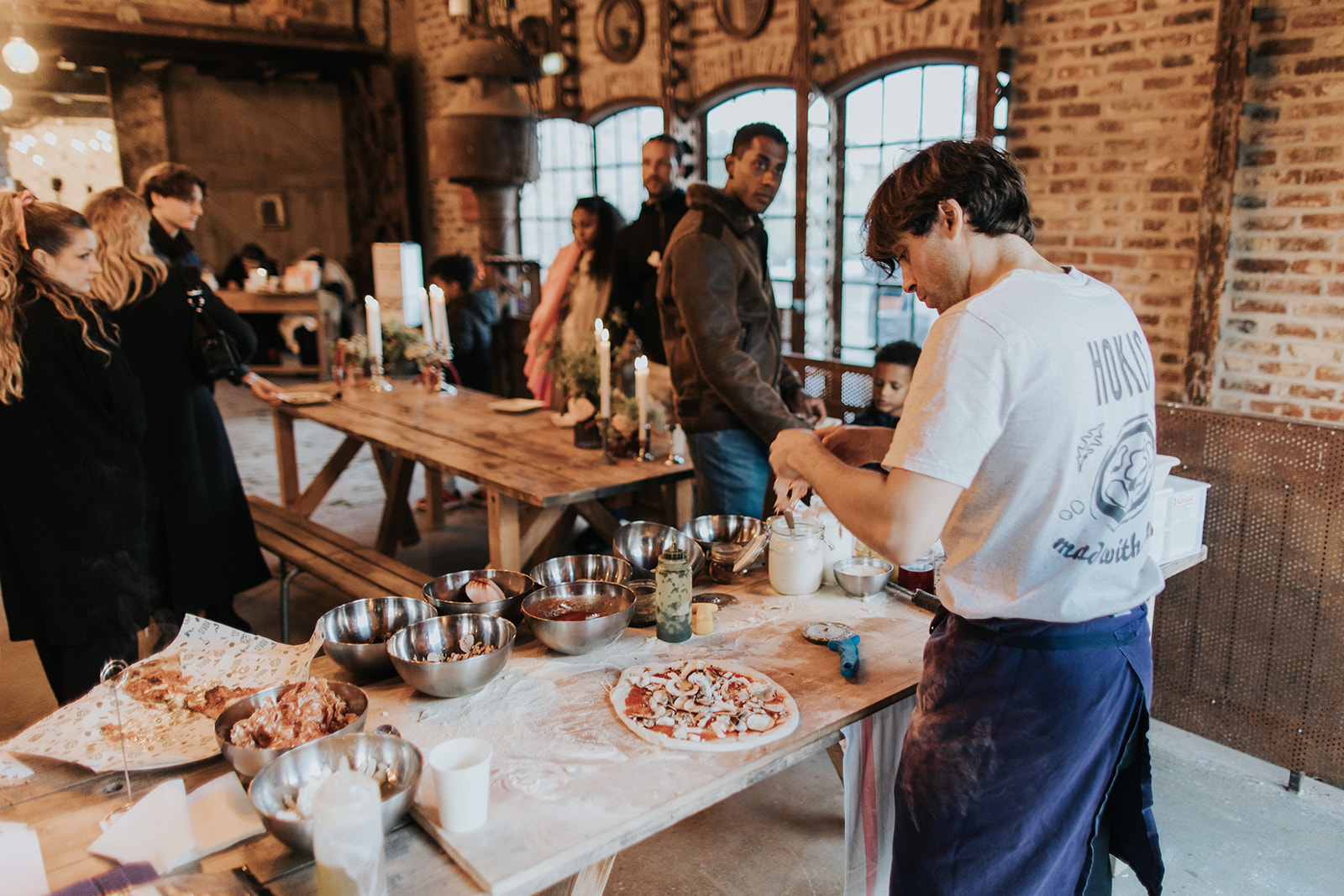 Chef garnissant une pizza sur une table de travail lors d'un marché gastronomique