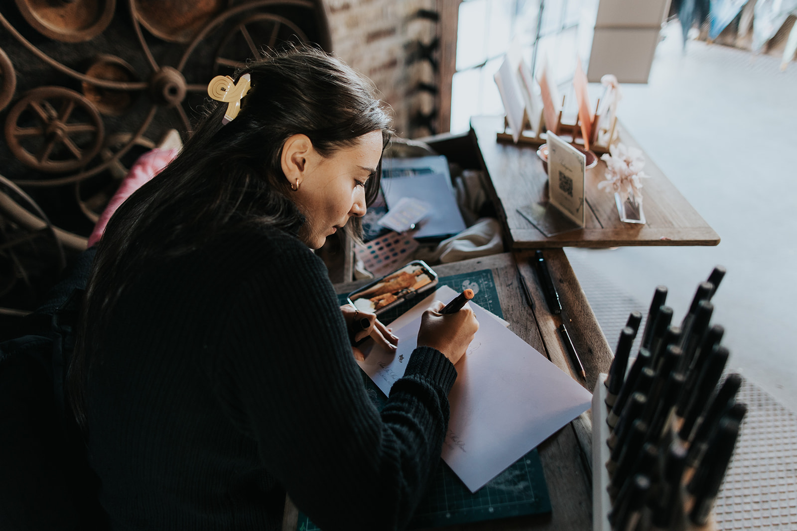 Artiste pratiquant la calligraphie à une table en bois lors d'un événement
