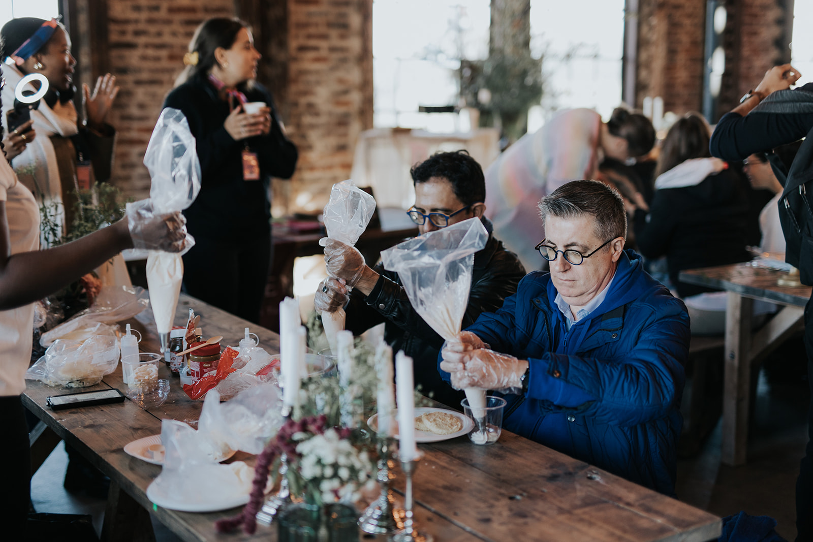 Participants utilisant des poches à douille lors d'un atelier culinaire dans un espace en briques
