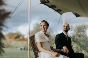 Couple de mariés assis sous un voile de tente lors d'une cérémonie en plein air en automne